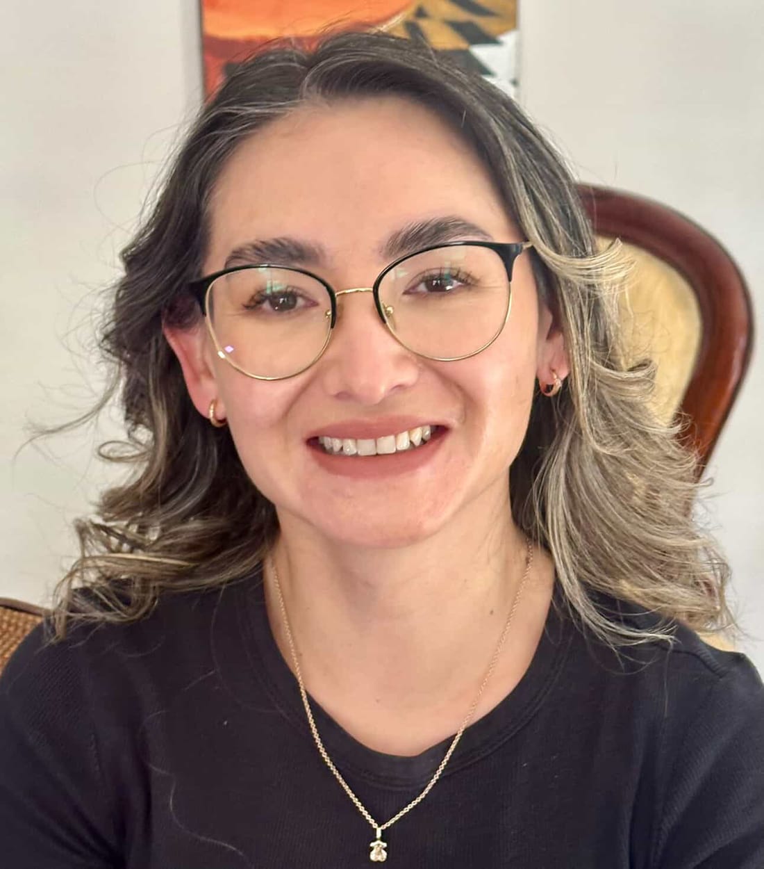 Mujer sonriente con anteojos y un maquillaje luminoso de acabado natural