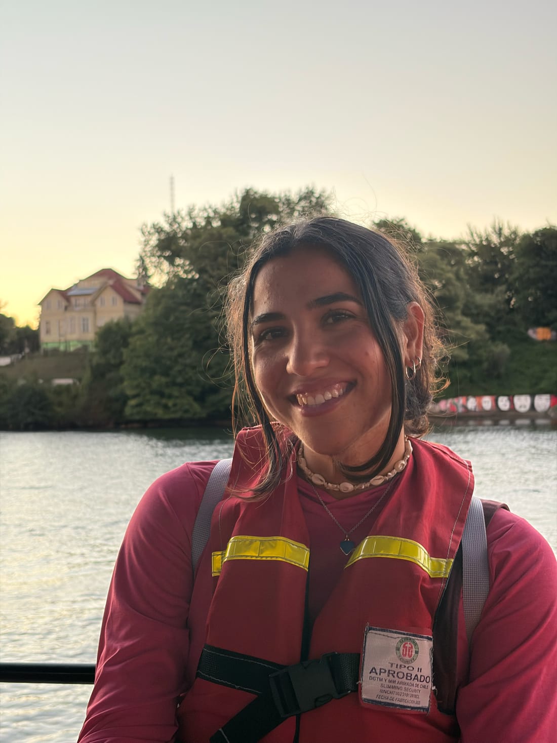 Antonella Dinis sonriendo al aire libre con un chaleco de seguridad burdeos